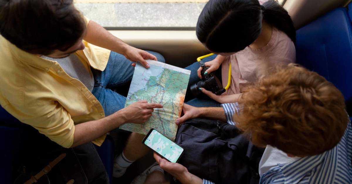 Amigos consultando mapa e celular, essenciais para dicas de ser um viajante, não turista.