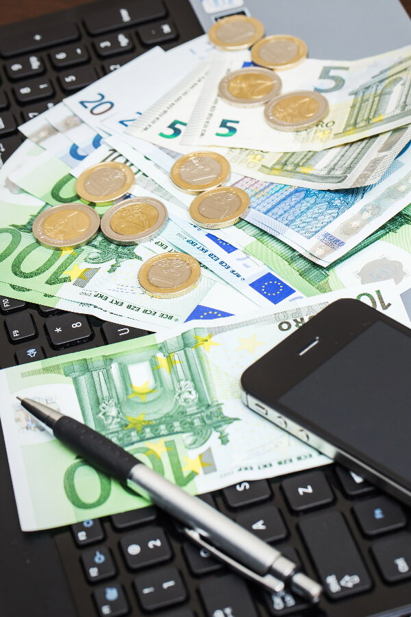 Calculadora, euros e bilhete de avião na mesa