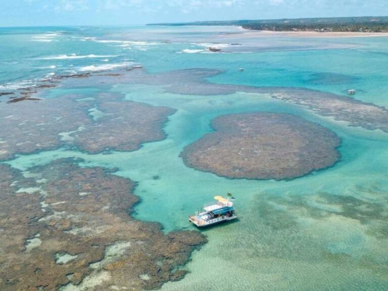 Barco sobre piscinas naturais de coral em São José da Coroa Grande, um espetáculo da natureza