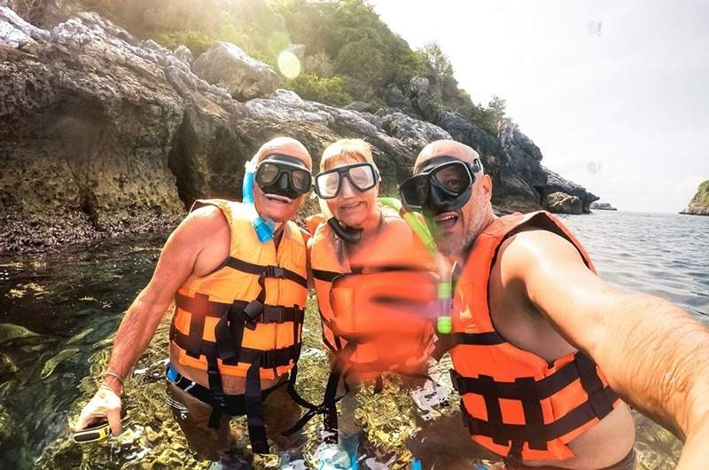 Casal sênior sorridente em equipamento de snorkel, desfrutando do turismo sênior aquático