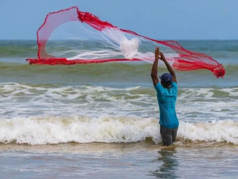 Pescador em ação, rede voando sobre ondas, promessa de frutos do mar frescos