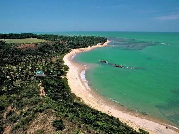 Visão aérea da serena Praia de Barra de Tabatinga, RN, com suas águas verde-azuladas e faixa de areia dourada