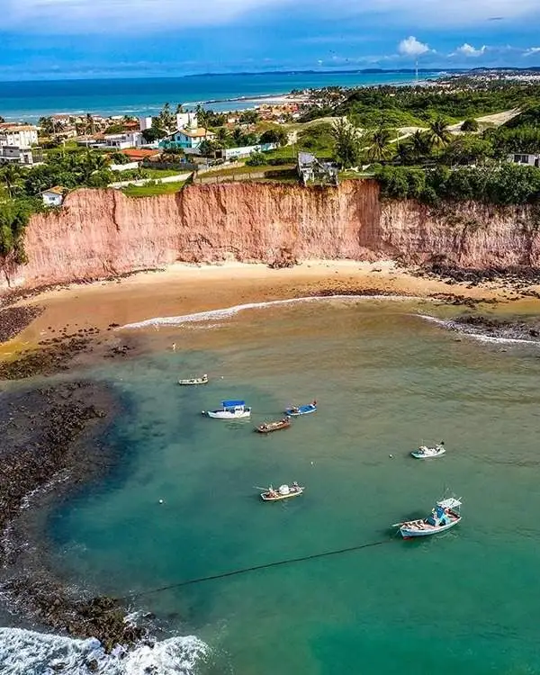 Barcos de pesca ancorados perto de falésias cor de rosa na Praia de Barra de Tabatinga, RN.