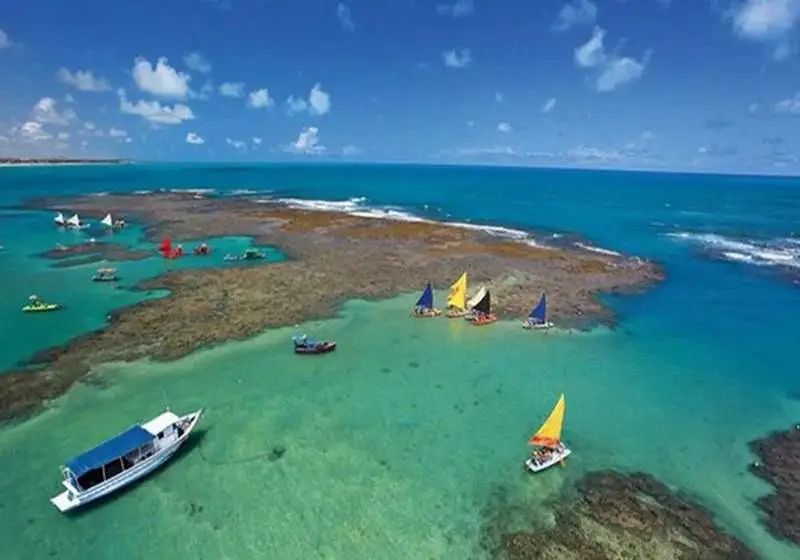 Jangadas multicoloridas flutuam nas águas turquesa dos recifes de Porto de Galinhas, Brasil