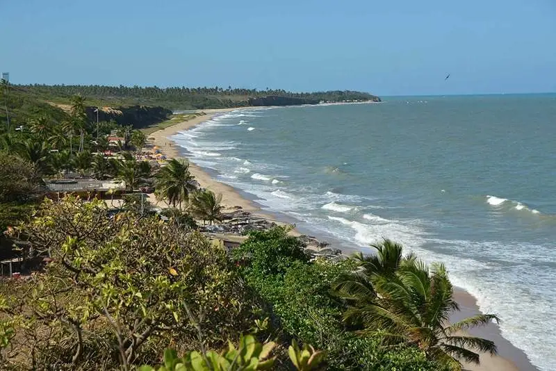 Praia do Sol em João Pessoa com vegetação exuberante e mar azul.