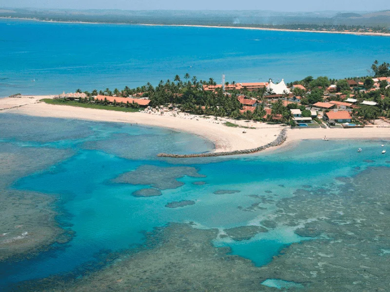 Vista aérea da Praia de Serrambi com suas águas azul-turquesa e recifes de coral, um destino ideal para amantes da natureza.